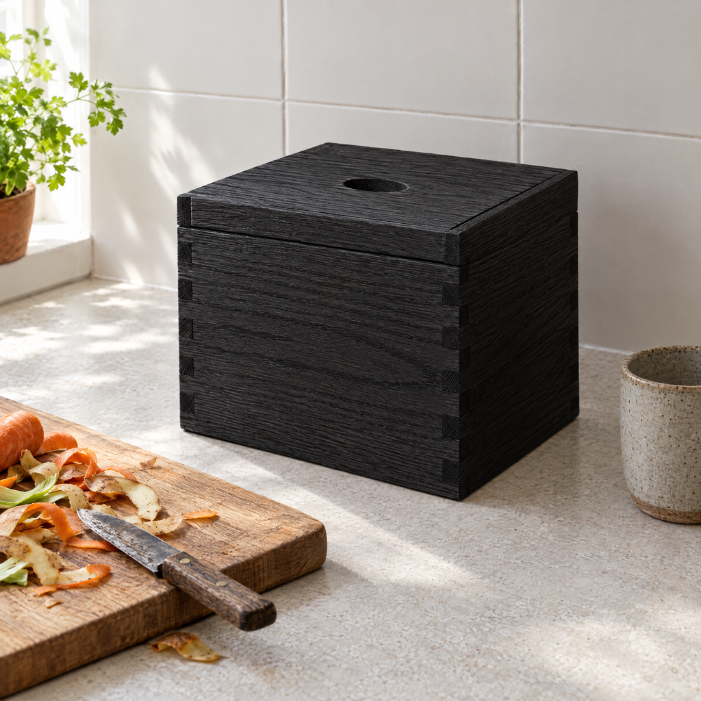 Black ash compost box on a stone worktop beside a chopping board