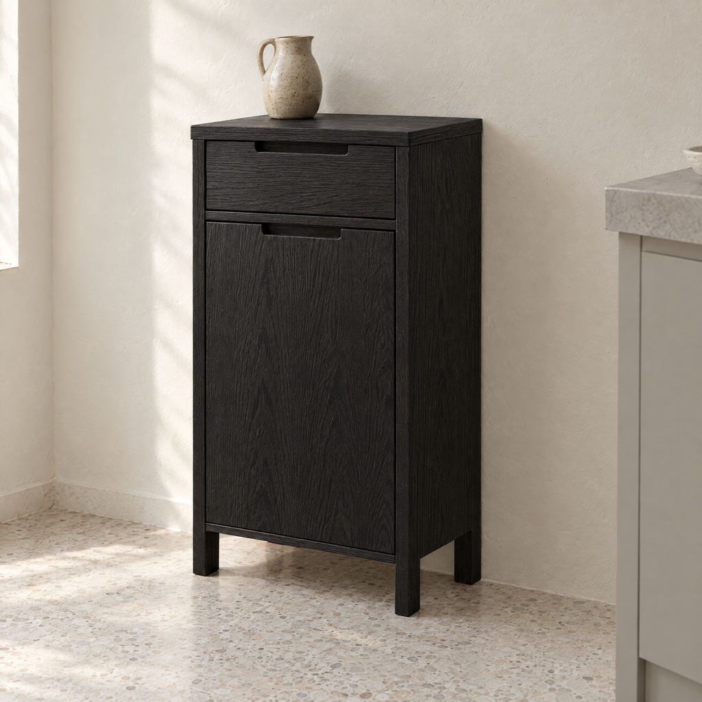 Black ash bin cabinet with drawer against a plaster wall in a kitchen