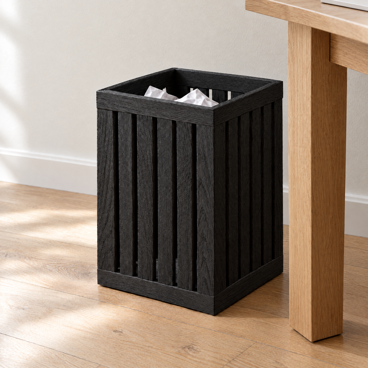 Black ash slatted paper bin beside an oak desk